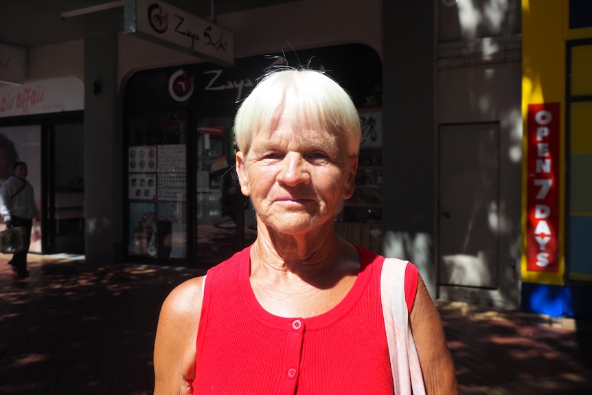 An older woman with short hair looks directly into camera with neutral expression on face