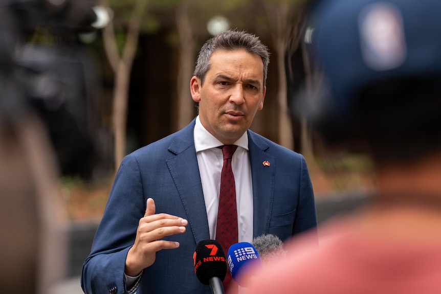 Blair Boyer gestures with a hand while speaking to media on a street