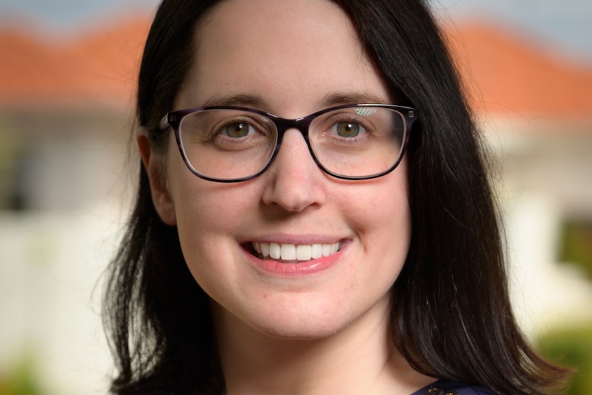 A close-up shot of a woman's face wearing glasses