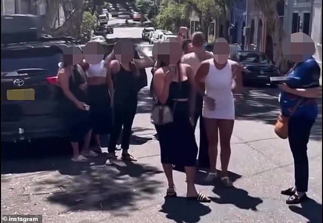 A group of girls dressed in figure-hugging 'body-con' clubbing dresses and carrying handbags taunt others to fight