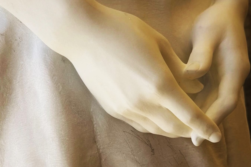 Close-up detail of hands of a marble sculpture.