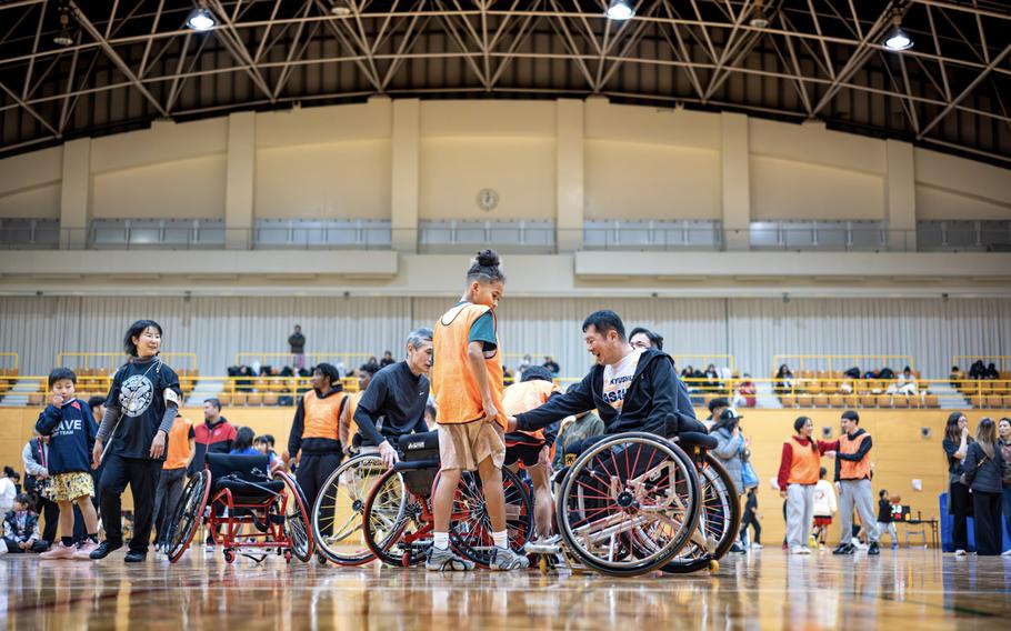 
A group of athletes in wheelchairs on a gymnasium floor 