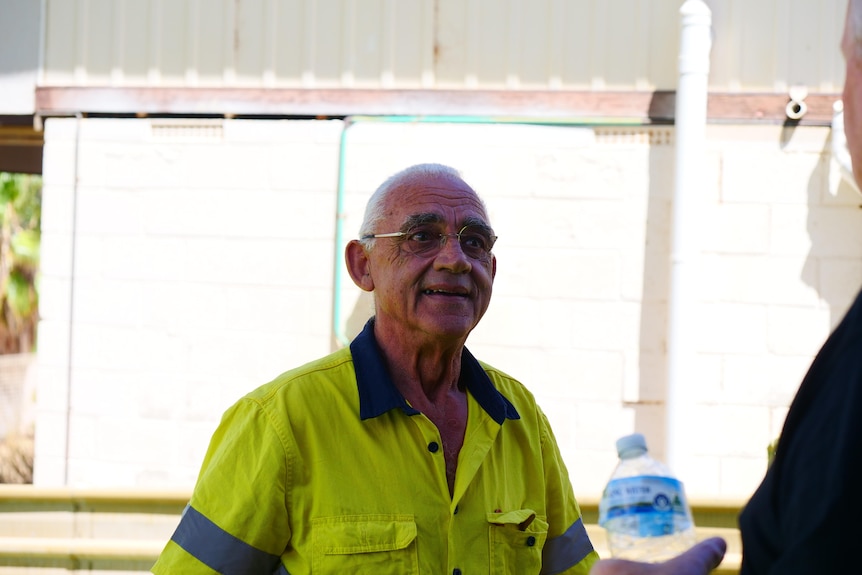 Head and shoulders photo of a man in a yellow high shirt with glasses