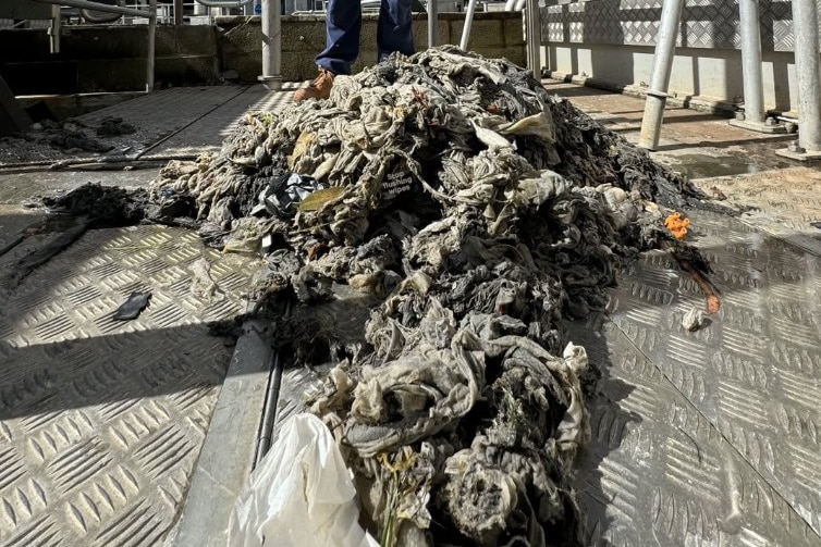 A man stands next to a wet, greasy fatberg.