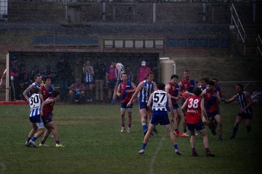 A pack of footballers tussle during a country football game.