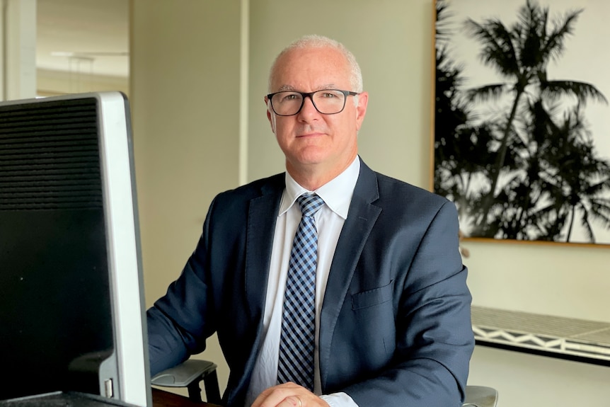 A man in his 50s looking at the camera in a suit.