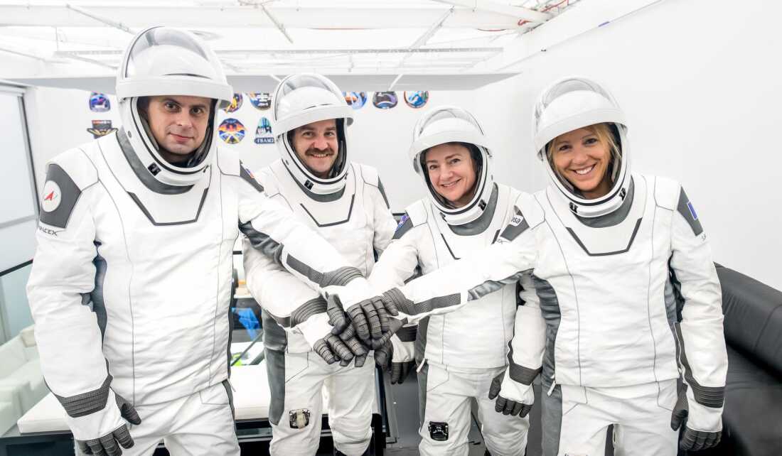 The four members of NASA’s SpaceX Crew-12 mission stand with a "hands in" pose while wearing their spacesuits.