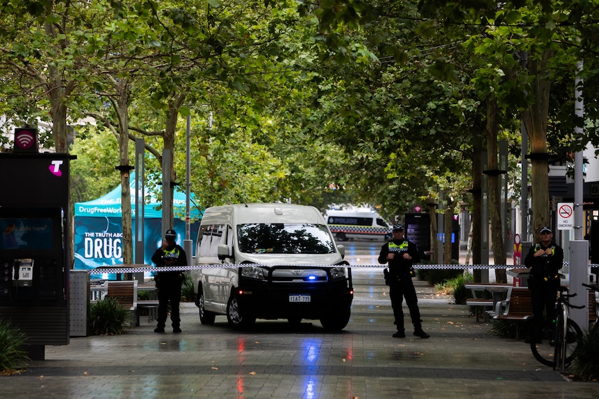 Police officers stand behind police tape blocking access to a pedestrian mall.