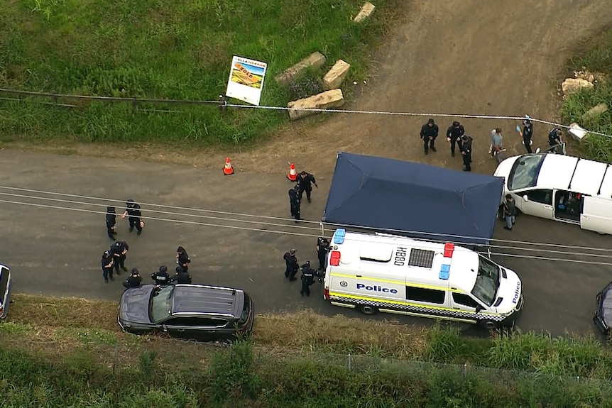 Police officers and vans parked in bushland.