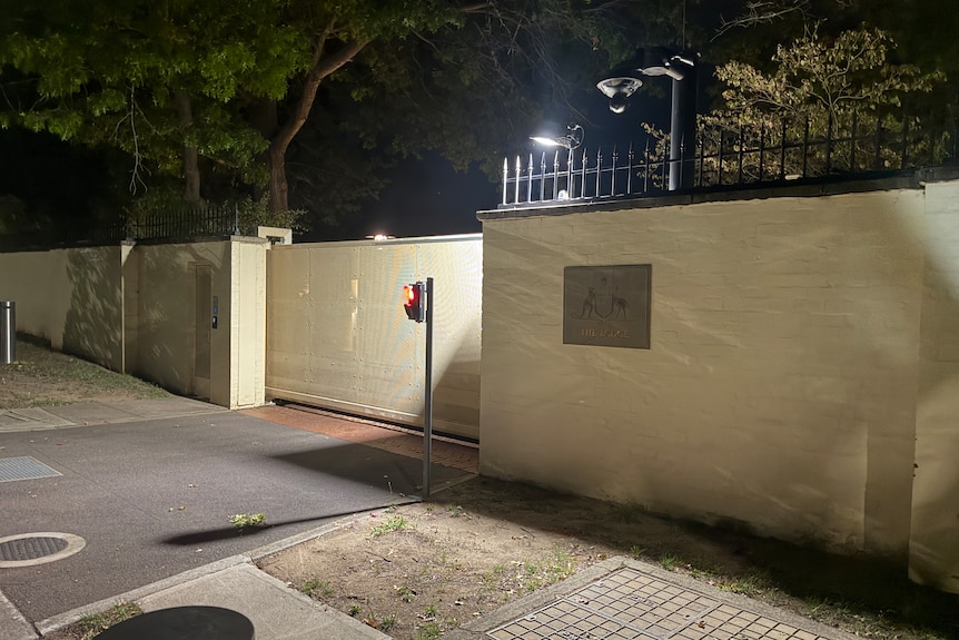 An external view of the gates of The Lodge at night, showing a sign and a light.