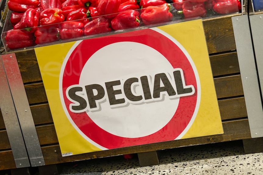 Close up of a white, yellow and red SPECIAL sign on a tray of capsicums inside a Coles Supermarket.