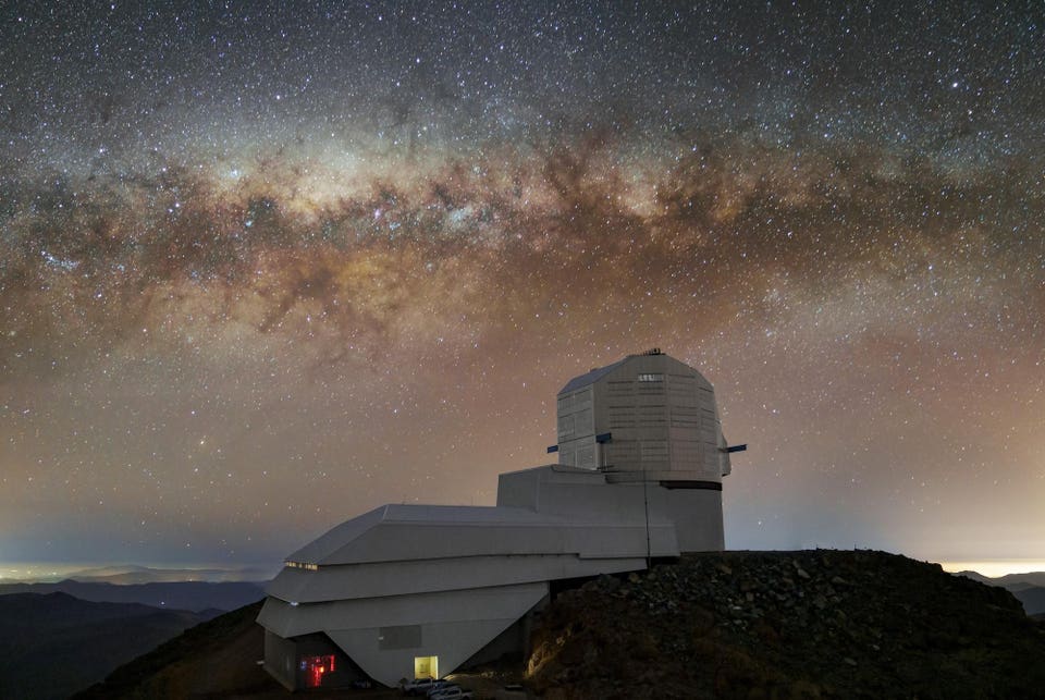 A large observatory on a mountain with the Milky Way galaxy visible in the sky.
