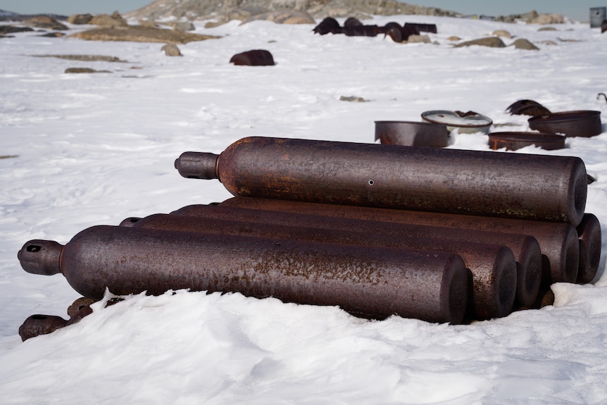 Rusting gas bottles stacked up in snow environment.