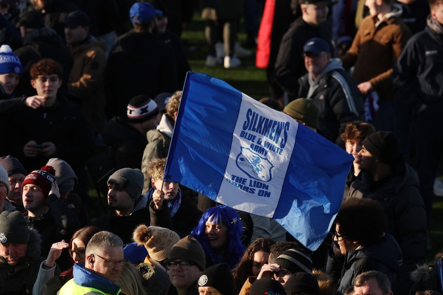 A large crowd of people, including one holding a flag.