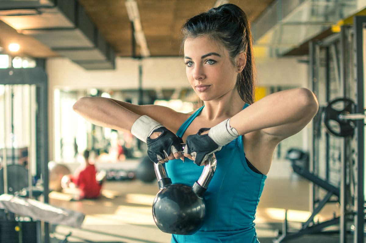 Young woman working out with a kettle bell in the gym (stock photo)