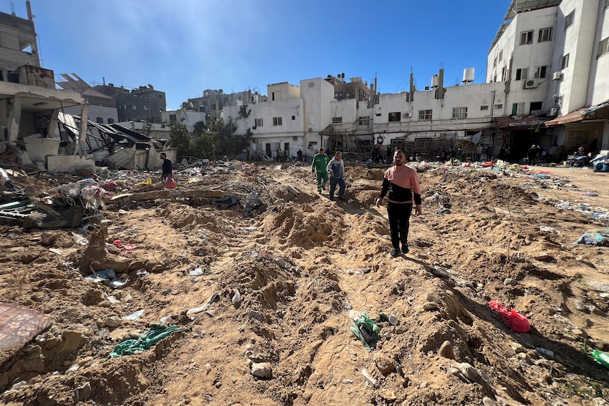 People walk through the rubble of a building