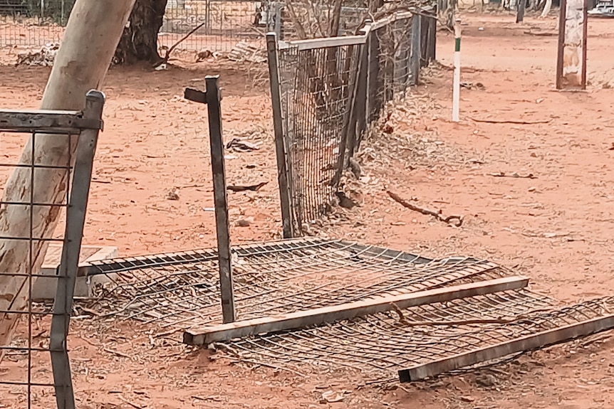 A broken fence in a dusty outback area.