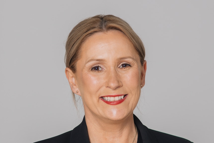 A woman with fair hair tied back smiles.