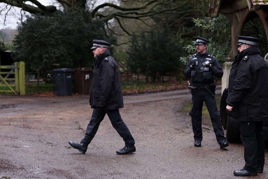 Three police officers stand outside Sandringham Estate.