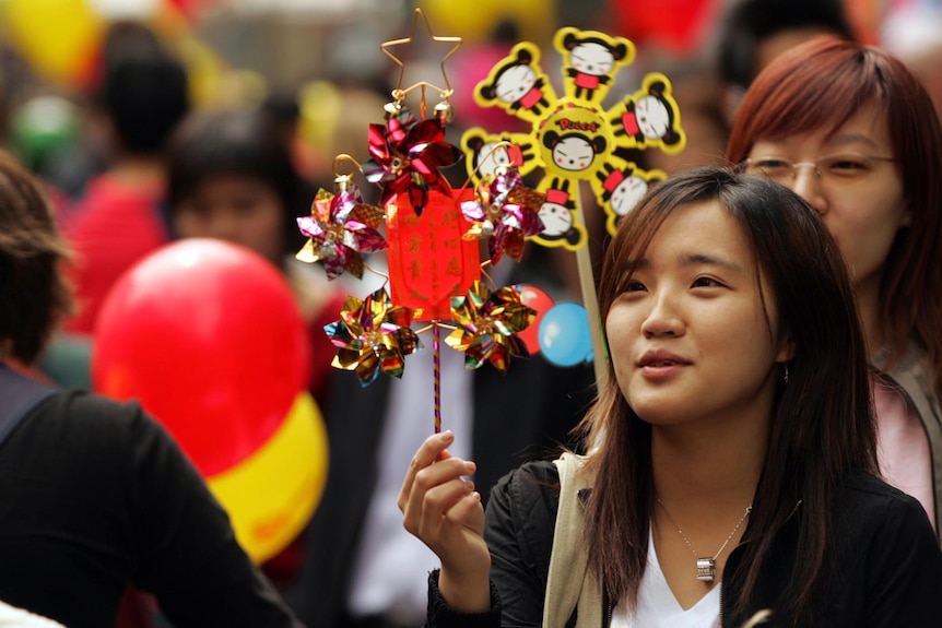 Two women hold up Lunar New Year pinwheels 