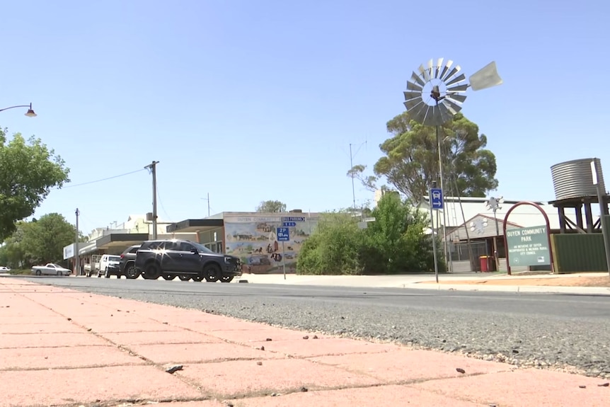 A sun kissed country town main street, with a steel windmill and a water tank