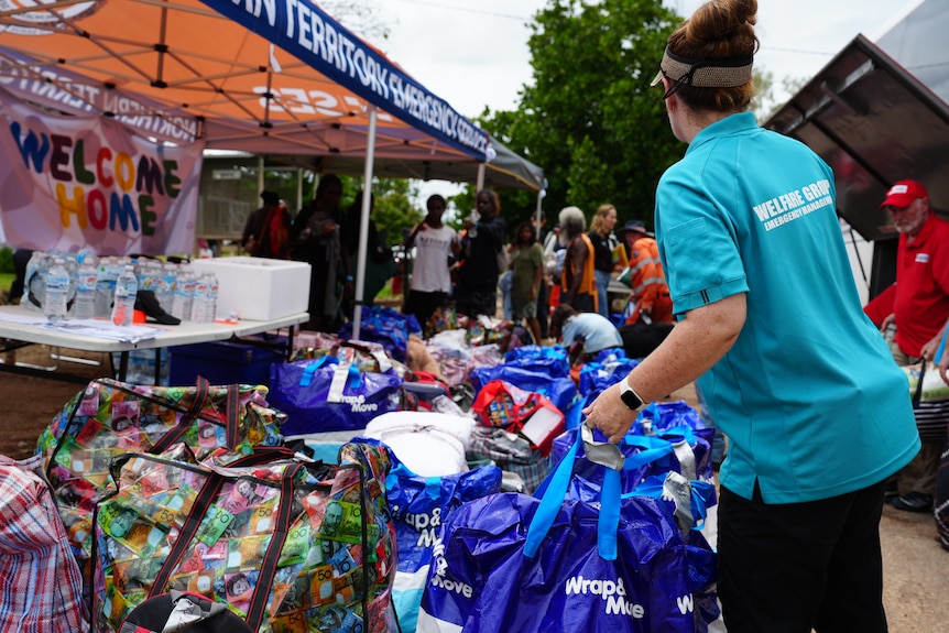 A government worker unloads bags from a bus