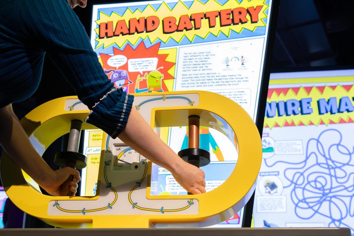Two hands holding metal rods as part of an interactive display