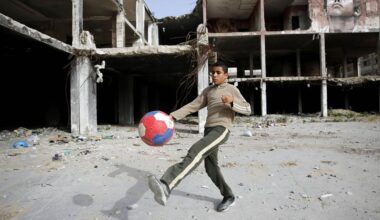 A boy plays football next a partially-destroyed building in Gaza City.