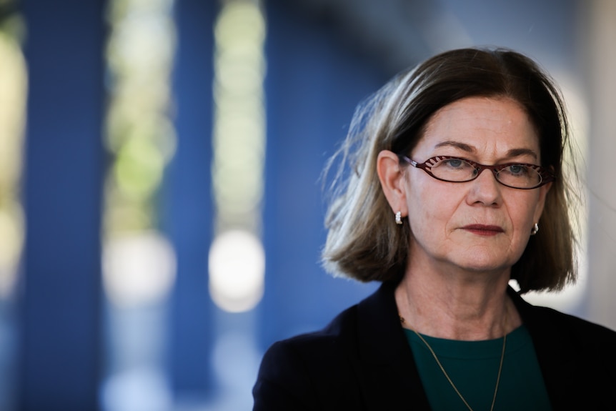 A close-up photo of Meredith wearing a dark green top, black jacket and glasses 
