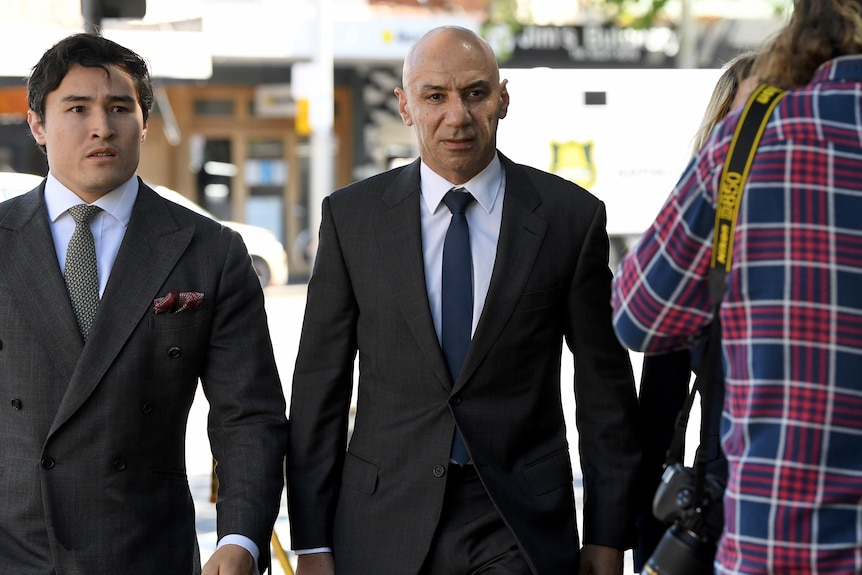 two mean walking on a street