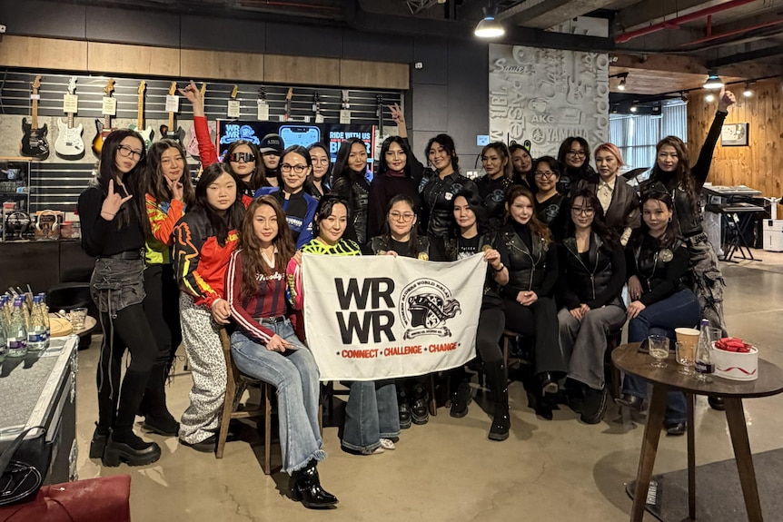 A large group of women hold a WRWR sign. 