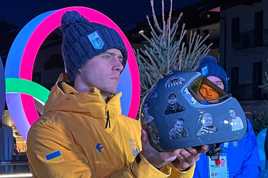 Ukraine's Vladyslav Heraskevych holds up his crash helmet in front of Olympic rings