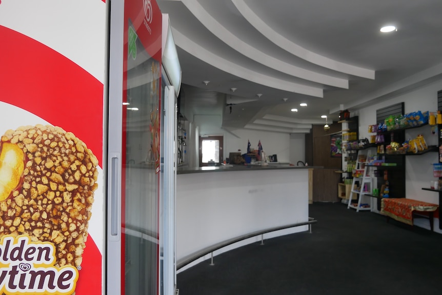 A shabby shop interior with shelves of lollies lining the walls.