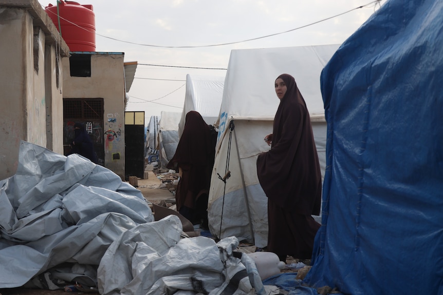 A woman wearing a burqa is spotted walking along a camp.
