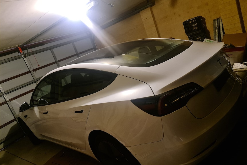 A white Tesla electric car parks at an indoor garage
