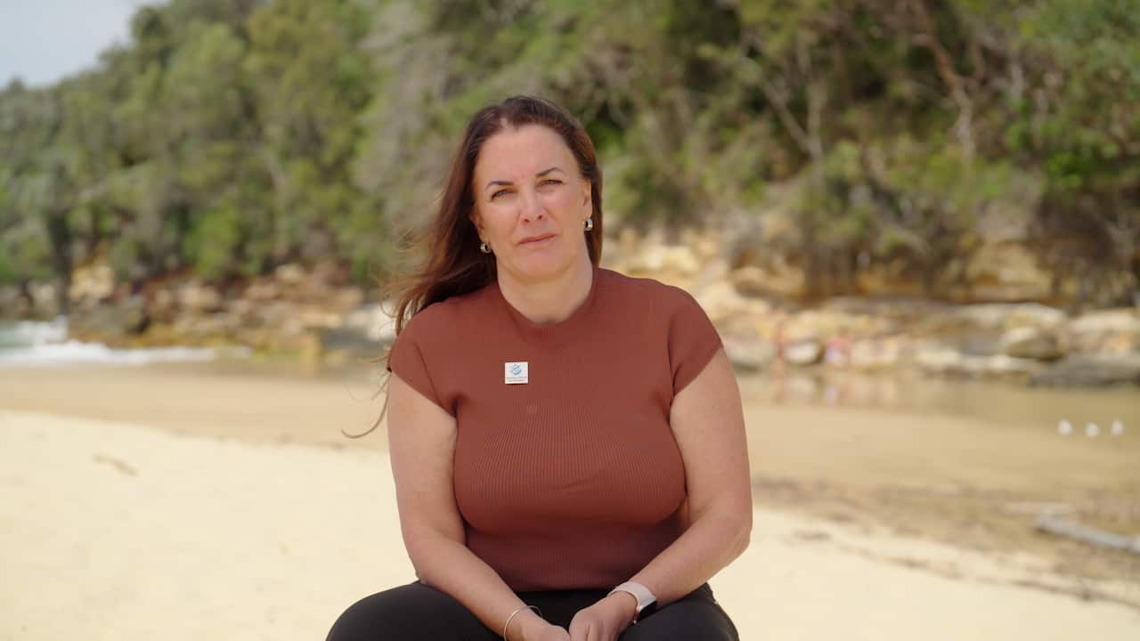 A woman sits on a beach. 