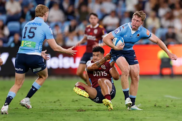 The Waratah’s Harry Potter is tackled by Hunter Paisami of the Reds, during their round one Super Rugby match.