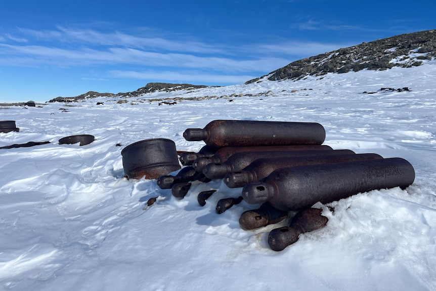 Stacked rusted gas bottles in a snow covered landscape.