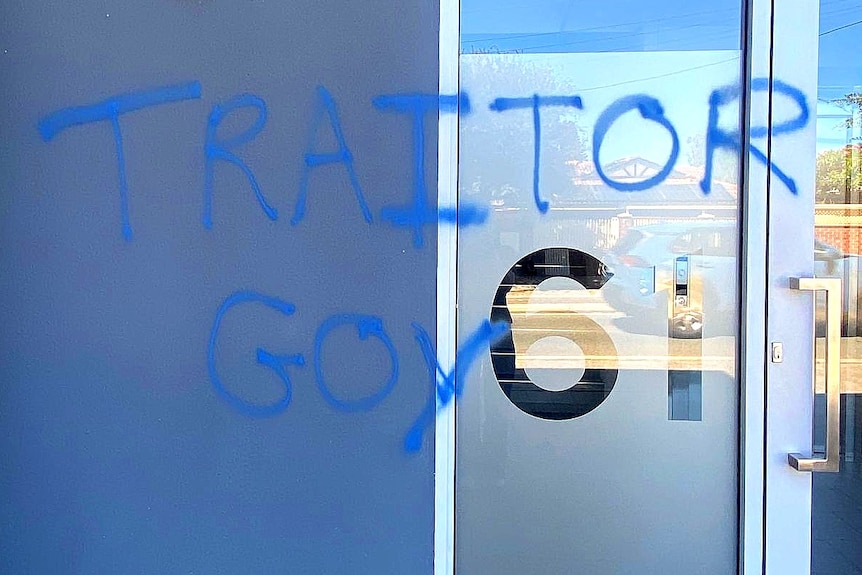 The words 'Traitor' and 'Goy' spray painted on a blue wall