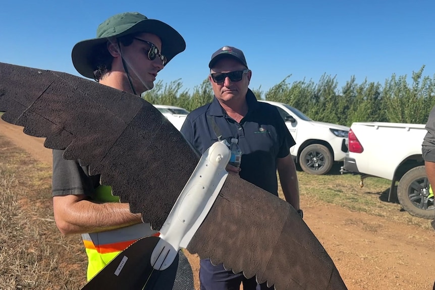 Two men holding the drones ahead of a test flight