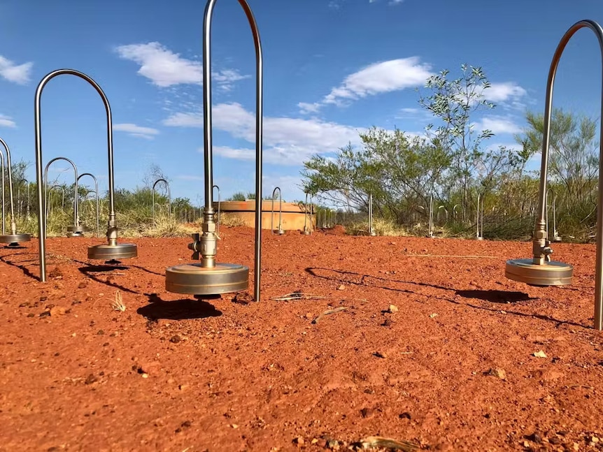 Arch-shaped metal detectors planted in red sand at the Warramunga station