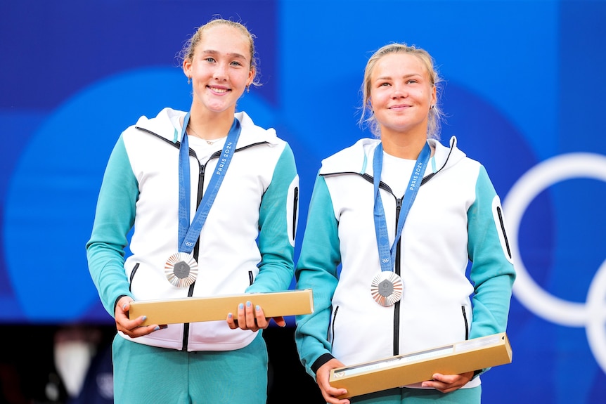 Two athletes hold up their medals after winning an Olympic tennis match 