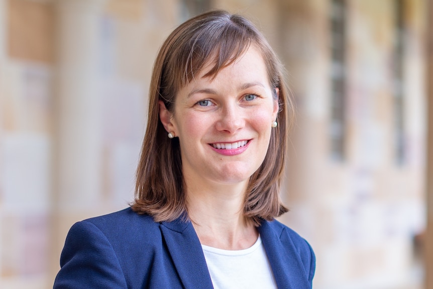 Woman in white blouse and blue suit standing in front of sandstone building