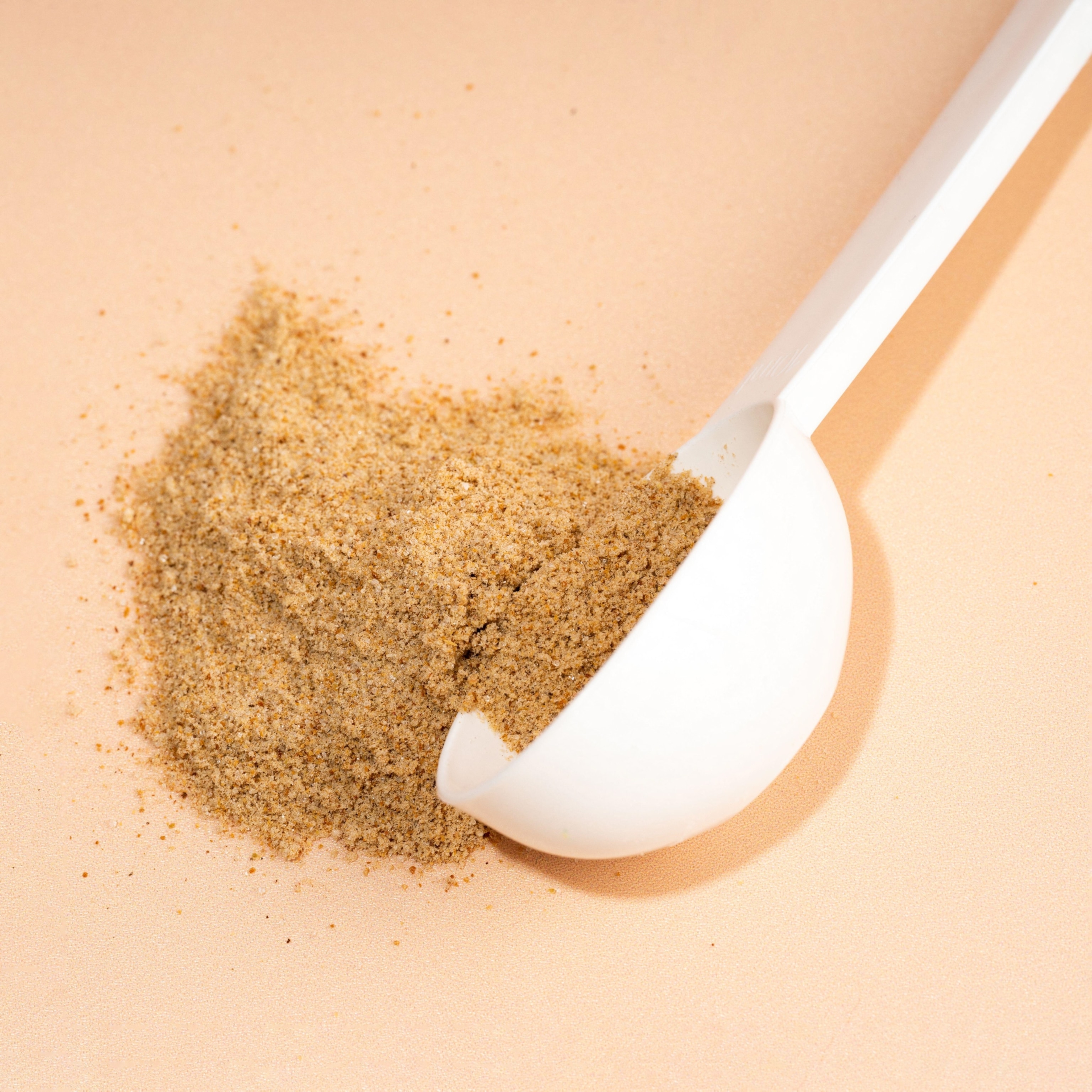 A scoop of fiber powder, spilling onto a beige background