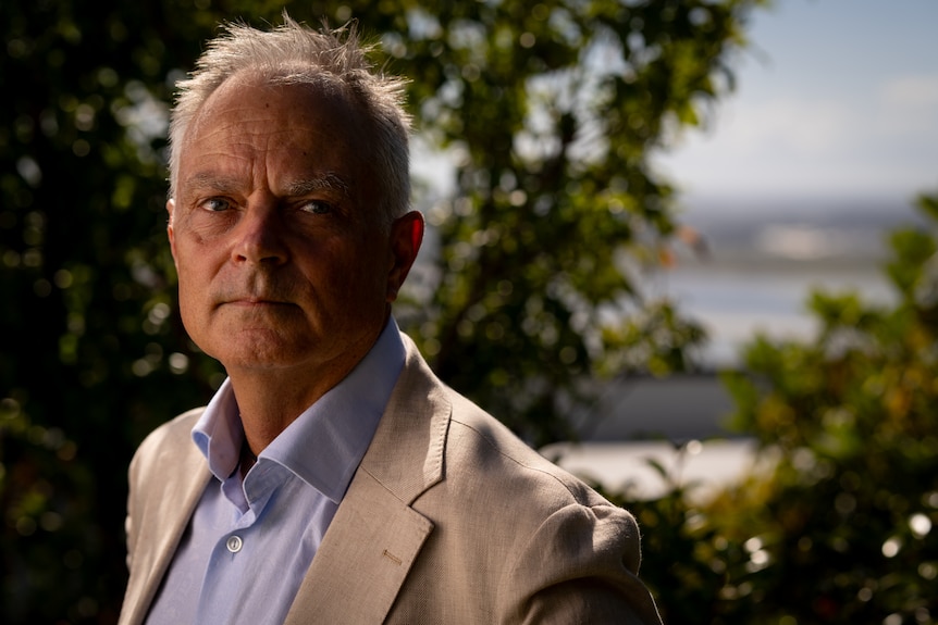 man in cream suit looks towards the camera