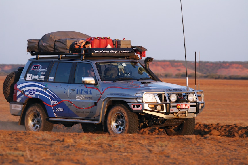 A silver branded car being driven along a dirt track