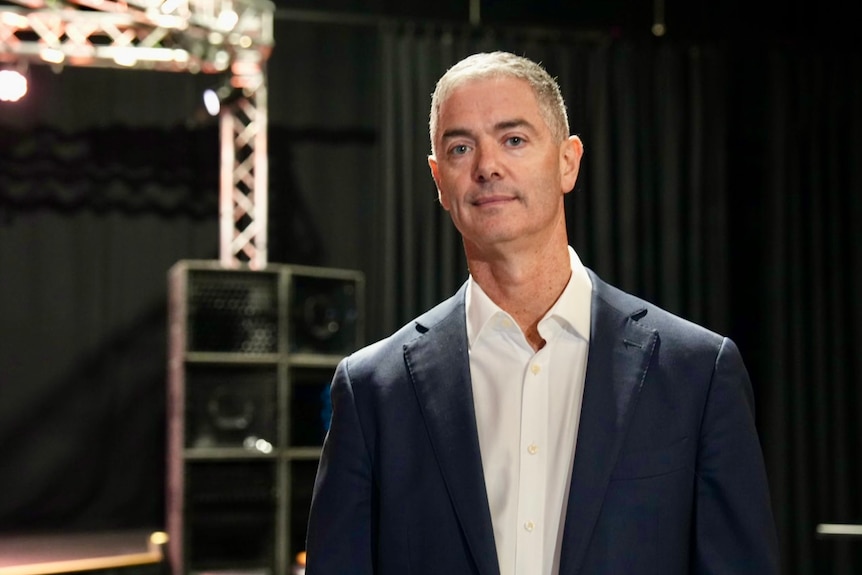 John Graham wears a suit jacket and poses for a photo in a theatre.