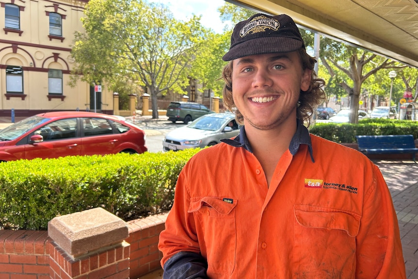 A young man in high vis overalls and a brown cap