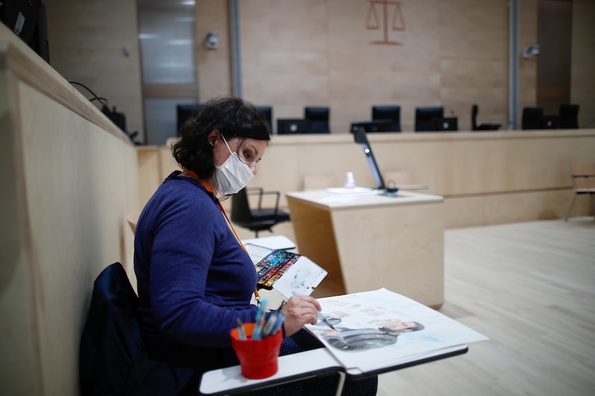 A artist inside a cubicle paints with watercolours. 