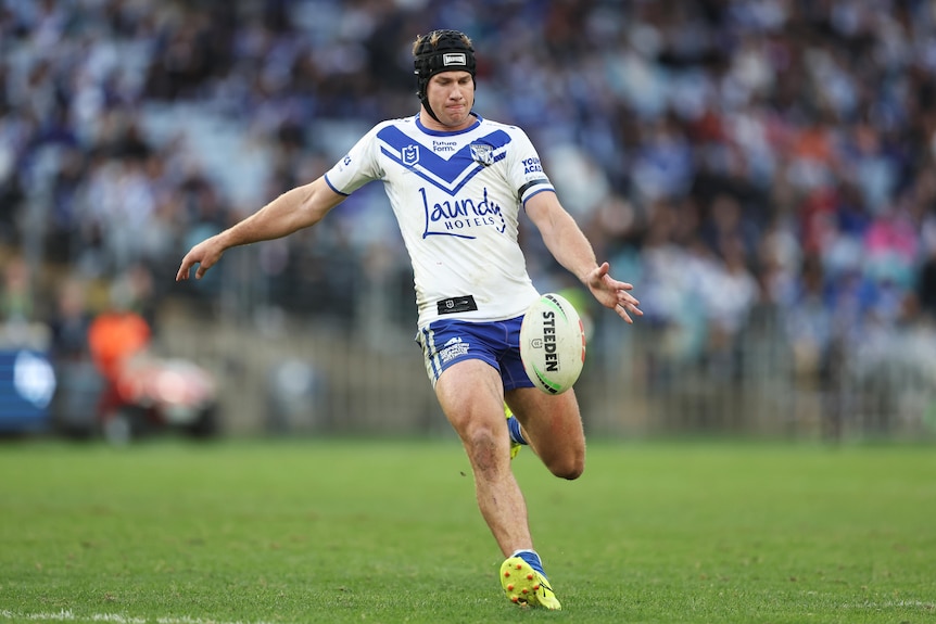 Matt Burton of the Canterbury Bulldogs drops the ball and winds up to kick it.